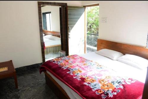 a bedroom with a bed with a floral blanket and a mirror at zoz mount abu in Jāmb