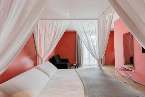 a bedroom with a large bed with white curtains at Quaint Boutique Hotel Xewkija in Xewkija