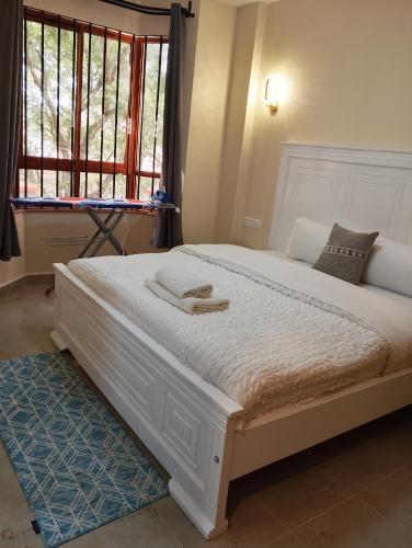a bedroom with a large white bed with a window at Kwame Homes in Nakuru