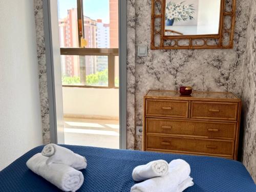 a bedroom with towels on a bed and a mirror at Apartments 1 & 2 Bedrooms, Gemelos 2 & 4, Levante Beach by Gestaltur in Benidorm