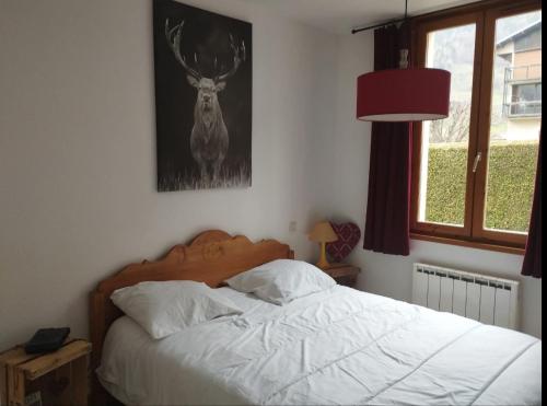 a bedroom with a bed with a deer picture on the wall at Le gîte du Val in Flumet