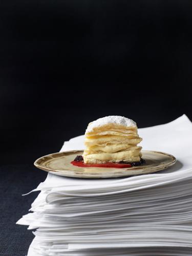 a piece of cake on a plate on a stack of papers at Gut Purbach in Purbach am Neusiedlersee
