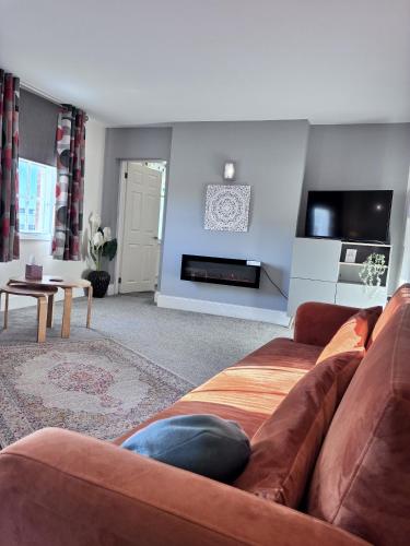 a living room with a brown couch and a fireplace at Historic Peel House Serviced Apartments in Burton upon Trent