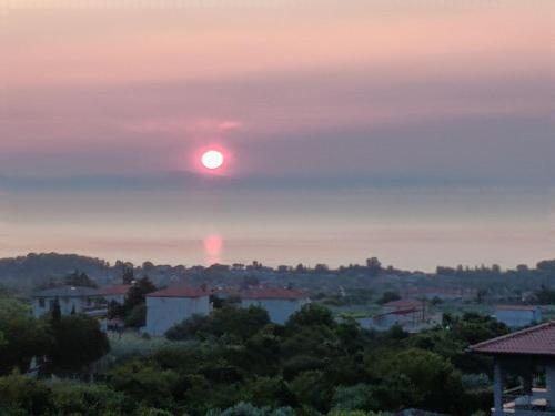a sunset over a city with the sun in the sky at Villa Anna in Leptokarya