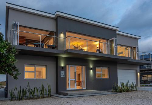 a house with a balcony with lights on at Whales Rest in Pearly Beach
