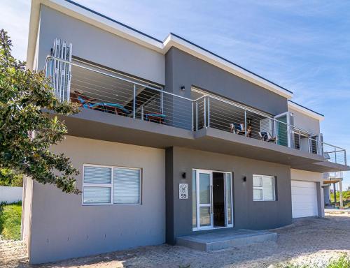 a house with a balcony with people sitting on it at Whales Rest in Pearly Beach