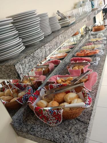 a buffet line with baskets of bread and plates at Hotel CANTO DA SERRA in Caldas Novas