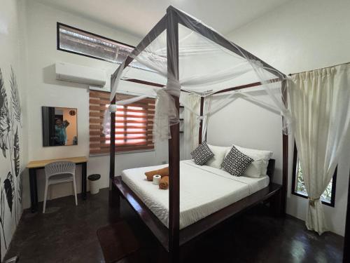 a bedroom with a canopy bed and a desk at Nutmeg Cottage SIARGAO 2BR exclusive whole house in General Luna