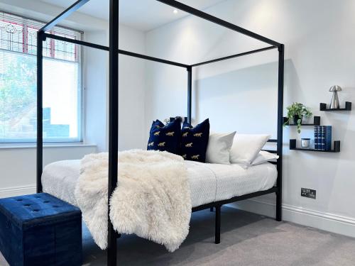 a bedroom with a black and white canopy bed with a white blanket at Central spacious town house in Exeter