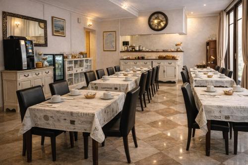 a restaurant with tables and chairs and a clock on the wall at Hôtel du Palais in Évian-les-Bains