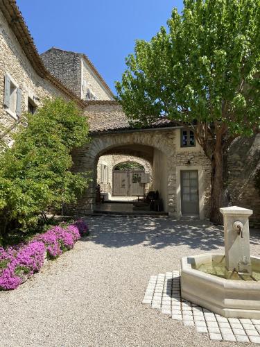 a building with an arch and a tree and purple flowers at Domaine Les Martins in Gordes