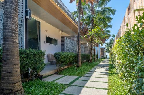 a sidewalk in front of a house with palm trees at The Strand Resort Samui in Bangrak Beach