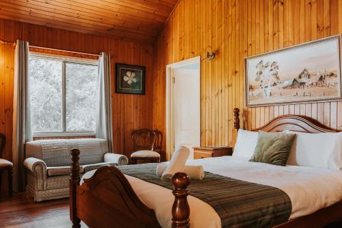 a bedroom with a bed and a chair and a window at Glasshouse Mountains Ecolodge in Glass House Mountains