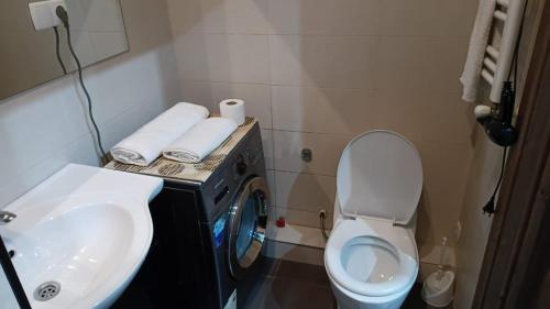 a bathroom with a toilet and a sink and a washing machine at Saburtalo VIP in Tbilisi City
