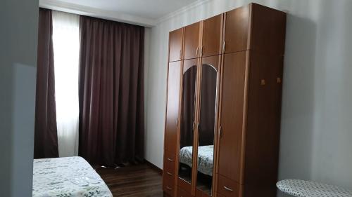 a large wooden cabinet in a bedroom with a bed at Saburtalo VIP in Tbilisi City