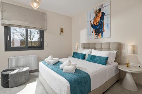 a white bedroom with a large bed with blue accents at Villa Kouros P&A in Áfra