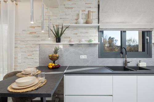 a kitchen with white cabinets and a sink and a table at Villa Kouros P&A in Áfra
