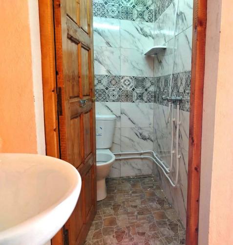 a bathroom with a toilet and a sink at Résidence Arinas in Al Barāwikah