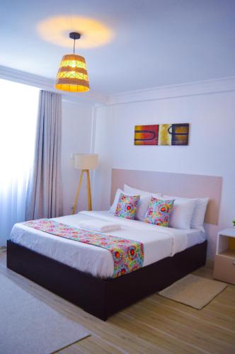 a bedroom with a large bed with colorful pillows at Olkeleo HummingBird Cottage in Naivasha