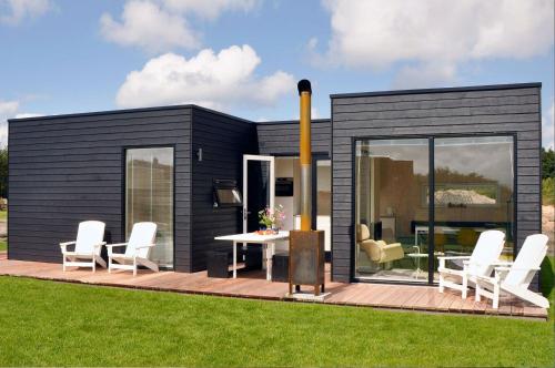 a black tiny house with a table and chairs at Noardewyn - Ecohuisjes Terschelling in Midsland