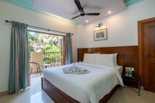 a bedroom with a large bed and a balcony at Victor Exotica An Indy Resort in Candolim