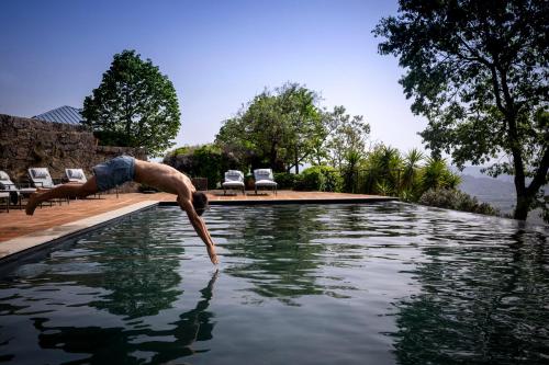a man jumping into a pool of water at TheVagar Countryhouse in Belmonte