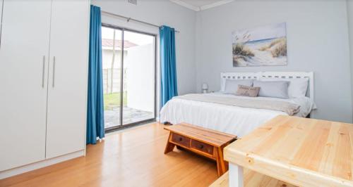 a bedroom with a bed and a table and a window at EBB Tide Guesthouse in Velddrif
