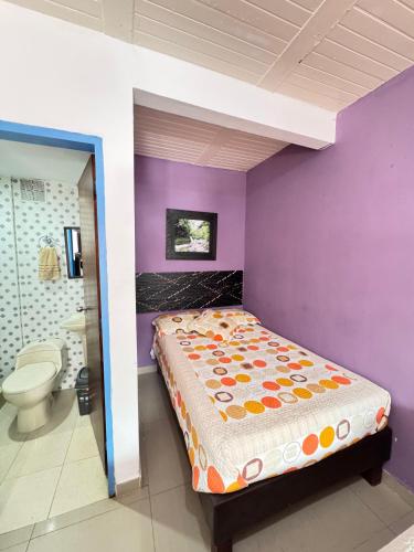 a bedroom with a bed and a purple wall at hospedaje casa de niebla in Salento