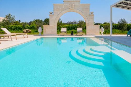 a swimming pool with an arch in the background at Villa Kalia Luxury by HDSalento in Aradeo
