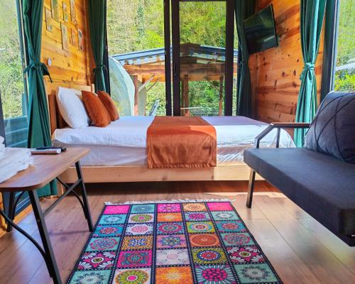 a bedroom with two beds and a couch and a rug at Lahza Tiny House in Çamlıhemşin