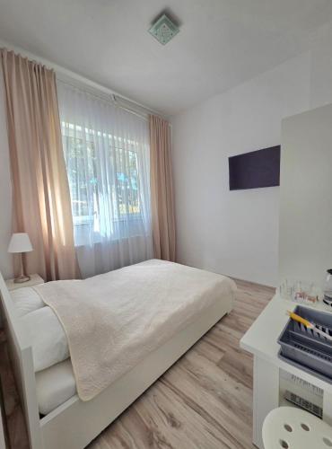 a white bedroom with a bed and a window at Villa Azalia in Jastrzębia Góra