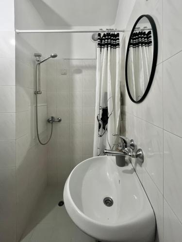 een witte badkamer met een wastafel en een spiegel bij Modern flat near downtown Plovdiv in Plovdiv