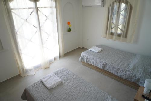 a bedroom with two twin beds and a window at Villa Noema Kineta in Kineta