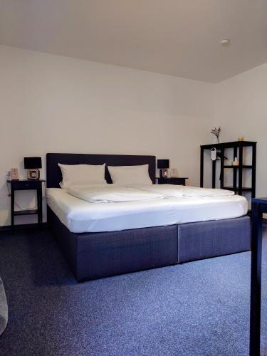 a large bed in a room with two tables at Hotel zur Schlemmerscheune in Weilerbach