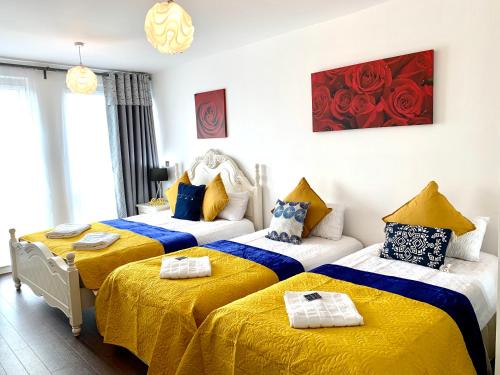 two beds in a room with yellow and blue at 2-Bedrooms Modern Apartment next to Velodrome, Lounge, Balcony, Parking, ABBA in London