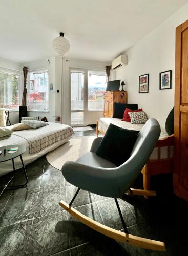 een woonkamer met een bed en een stoel bij Modern flat near downtown Plovdiv in Plovdiv