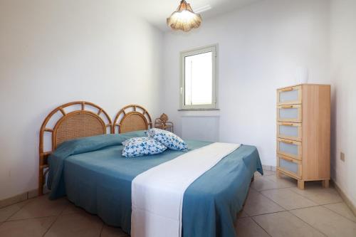 a bedroom with a bed with blue sheets and a dresser at Rosa Fronte Mare in Torre Mozza