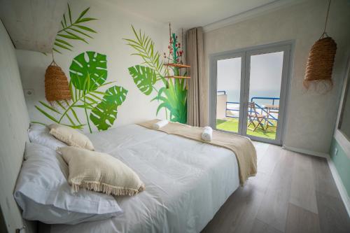 a bedroom with a white bed with a view of the ocean at Saltline Surf House Ericeira in Ericeira