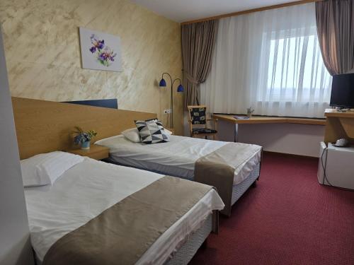 a hotel room with two beds and a desk at Iris Hotel in Oradea