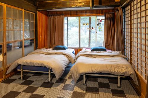 two beds in a room with a window at 淵明庵 in Fujikawa