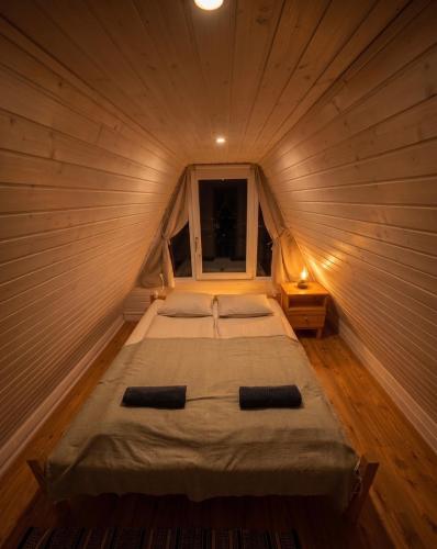 a bed in a wooden room with a window at Kamonkő Panoráma Kuckó in Szigliget