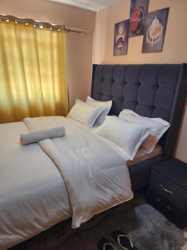 a bedroom with a large bed with white sheets and pillows at Pure excellence homes in Ruiru