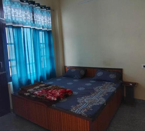 a bedroom with a bed with a blue comforter and two windows at Gate valley home stay in Dalhousie