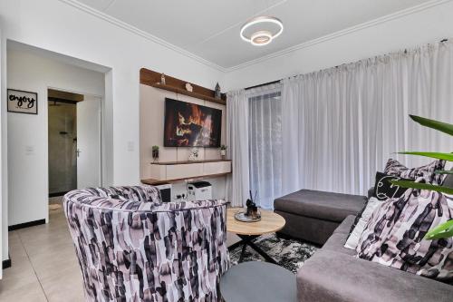 a living room with a couch and a table at Chanty Serenity- workstation, gym, backup power &Pool in Sandton
