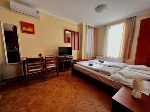 a bedroom with a bed and a desk and a television at Kolbászház Apartman in Gyula