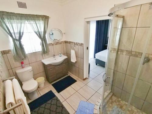 a bathroom with a toilet and a sink and a shower at Sleep@161 Benade Drive in Bloemfontein