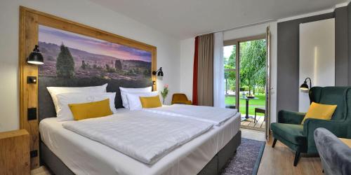 a bedroom with a large bed and a large window at Landhotel Schnuck in Schneverdingen