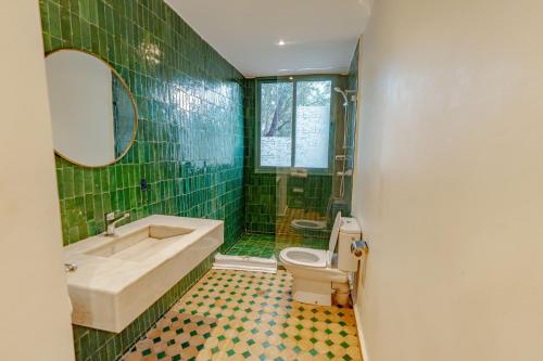 a bathroom with a tub and a toilet and green tiles at Ksar Shama - Atlas Mountain Retreat in Ouirgane