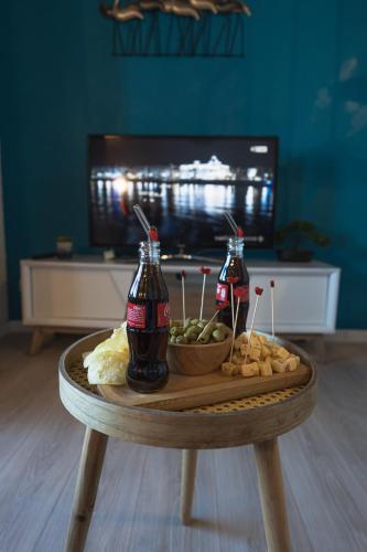 a table with two bottles of soda and a bowl of food at L'Horizon Bleu - Vue Etang - Parking - Plage à 5 min in Le Barcarès