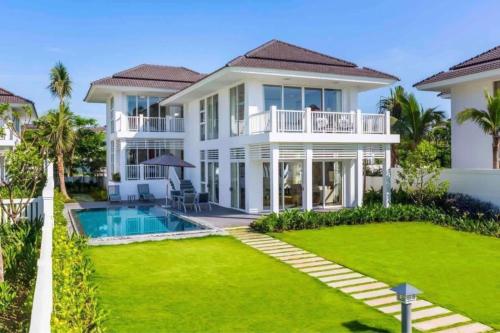 a large white house with a swimming pool and a yard at Luxury Private Pool Villas at Village Danang Resort in Danang